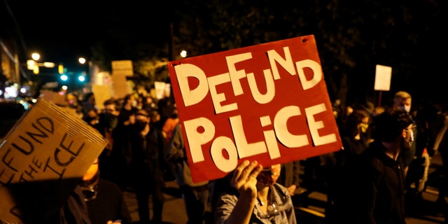 Protests carry defund the police posters during protest in New York over Daniel Prude
