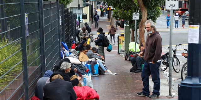 Photo shows homeless people in San Francisco standing and sitting outside in the Tenderloin district