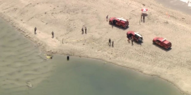 authorities at beach investigating barrel