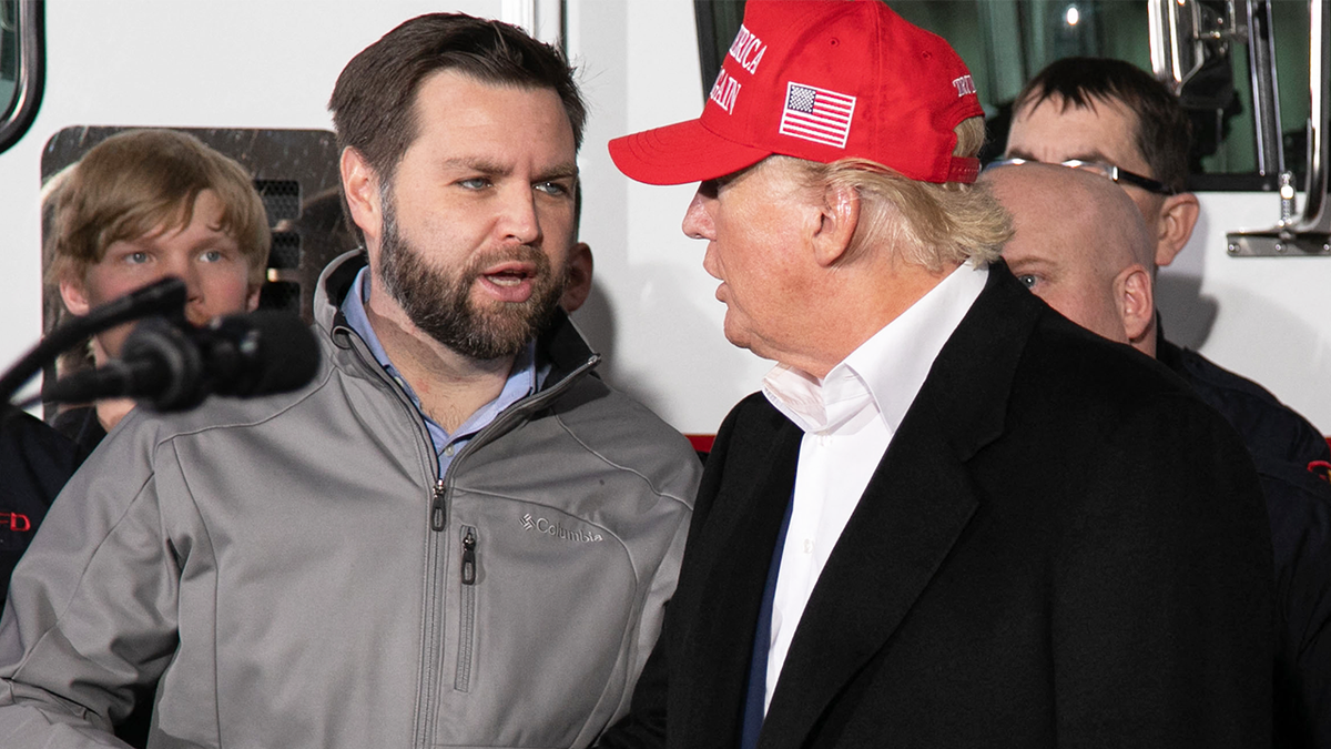 JD Vance in gray pullover, left; Donald Trump in red cap at right