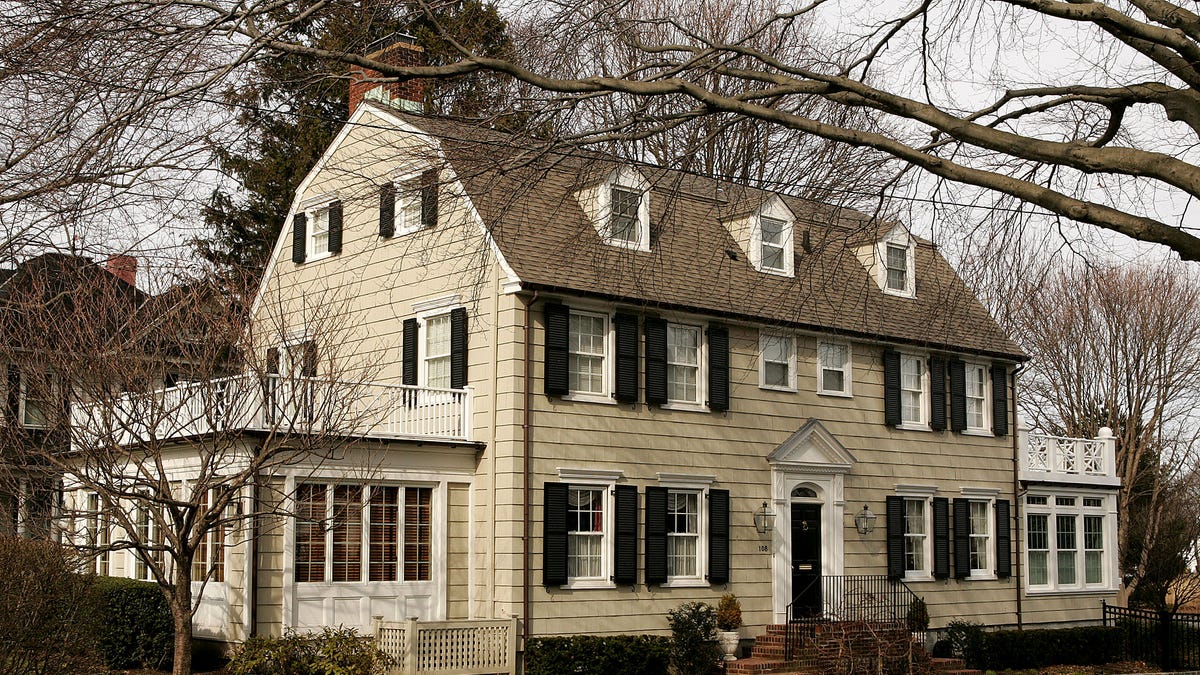 Amityville Horror House, colonial-style two-story home sits behind trees in fall photo