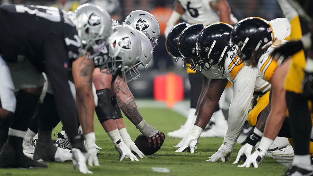 Raiders and Steelers players line up