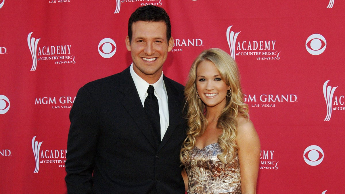 Carrie Underwood wears gold dress on red carpet with Tony Romo