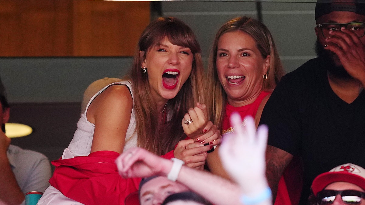 Taylor Swift holds onto a friend in a suite at the Kansas City Chiefs game and laughs