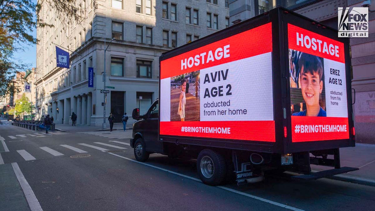 A truck displaying the names and photos of Israeli children taken as hostages by Hamas drives past New York University