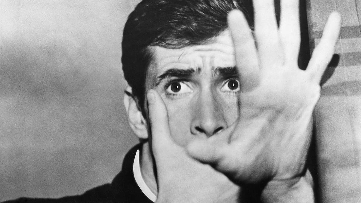Anthony Perkins covering his mouth with one hand