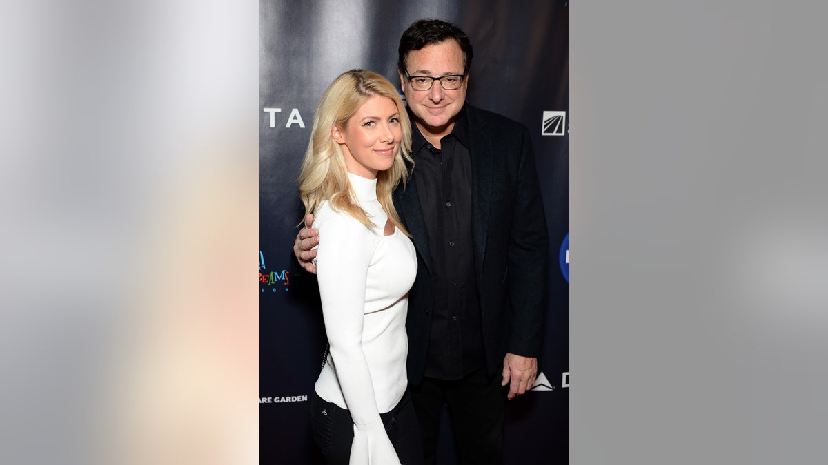 Kelly Rizzo wearing a white turtleneck with Bob Saget wearing a black suit