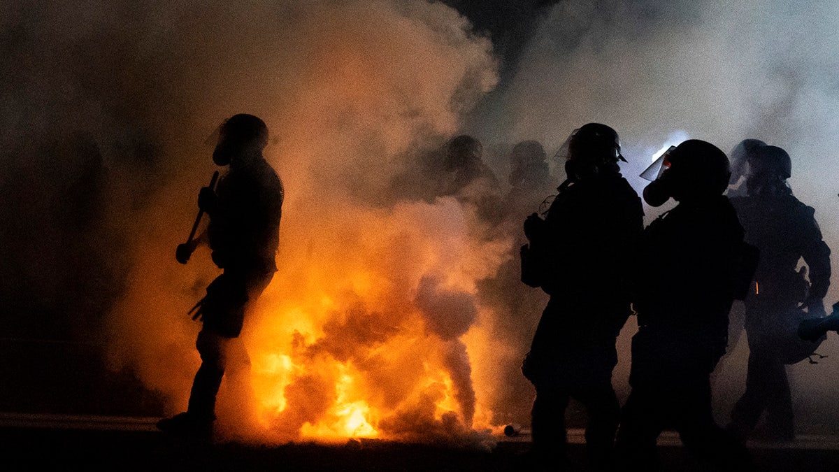 Oregon State Troopers and Portland police advance through tear gas