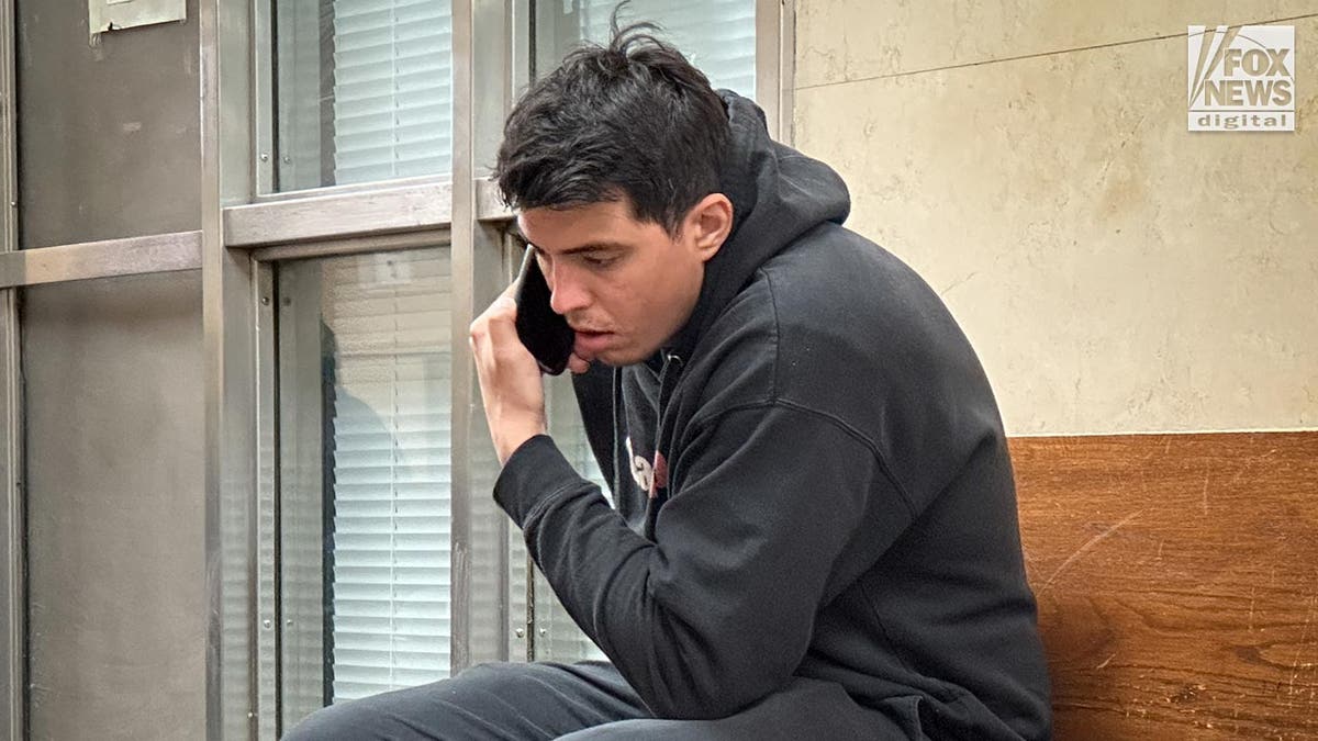 Long Island squatter, Brett Flores speaks on the phone in the hallway of court