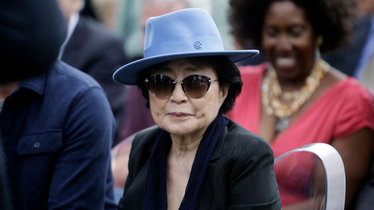 Yoko Ono is seen wearing a blue hat and sunglasses before the dedication ceremony for her permanent art installation, a sculpture called SKYLANDING, at Jackson Park in Chicago in 2017.