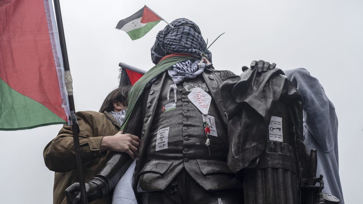 Students wrap Palestinian flag and Keffiye around the statue