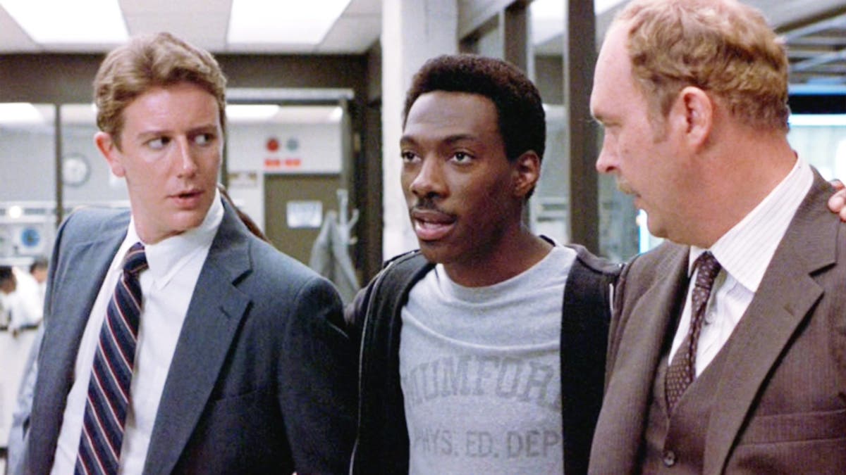 Judge Reinhold in a suit, Eddie Murphy in a grey t-shirt and black sweatshirt and John Ashton in a tan suit in "Beverly Hills Cop"