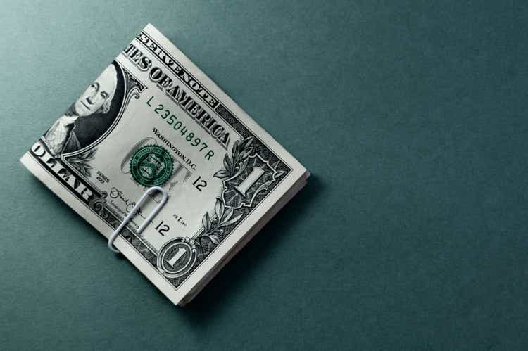 Bündel von US-Dollar-Banknoten in Nahaufnahme, isoliert auf graublauem Farbverlaufshintergrund. Papiergeld der Vereinigten Staaten von Amerika. Kopierraum, Farbraum. Finanzielles und wirtschaftliches Konzept