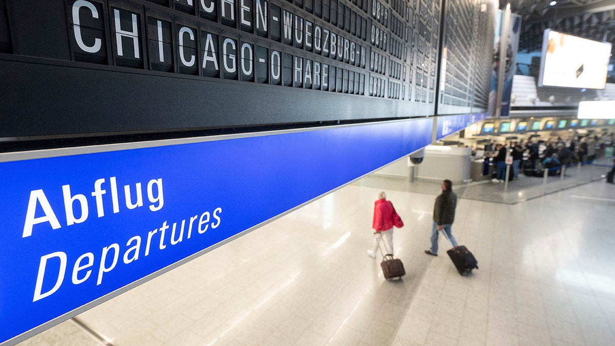 A flight to Chicago O'Hare in the USA is displayed on a board at Frankfurt airport under which passengers with suitcases walk along on Monday. 